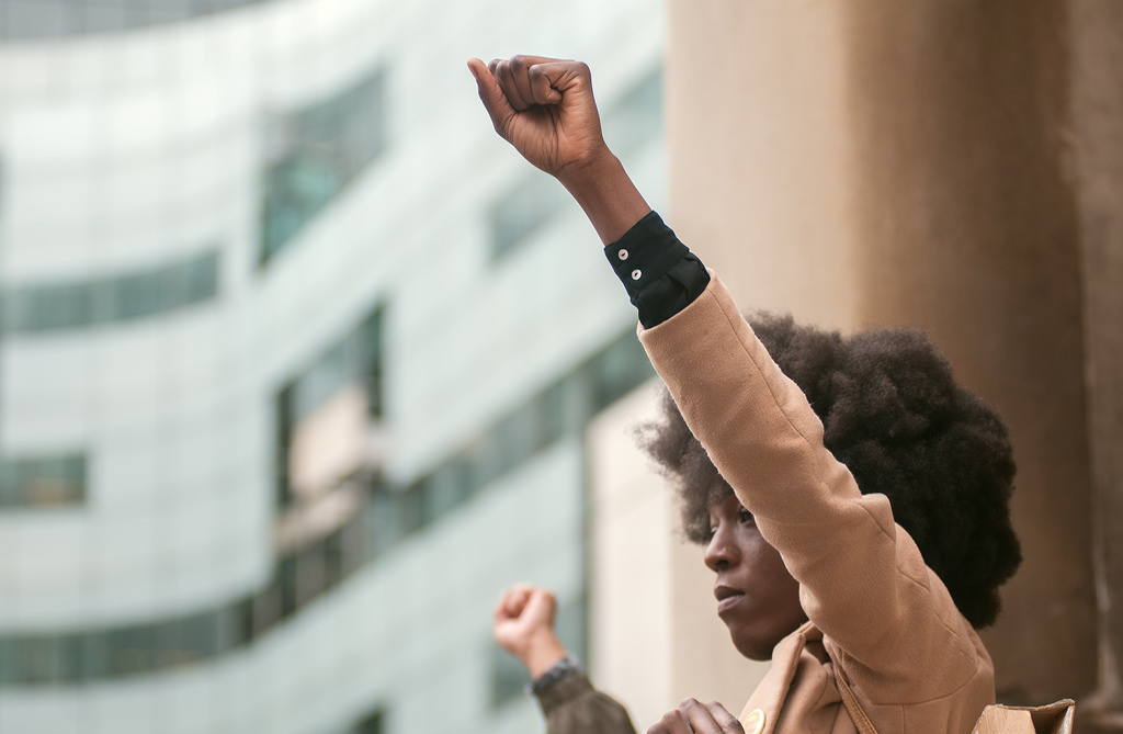 Person raising fist in protest outdoors