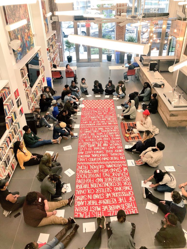 Group seated in library around red banner